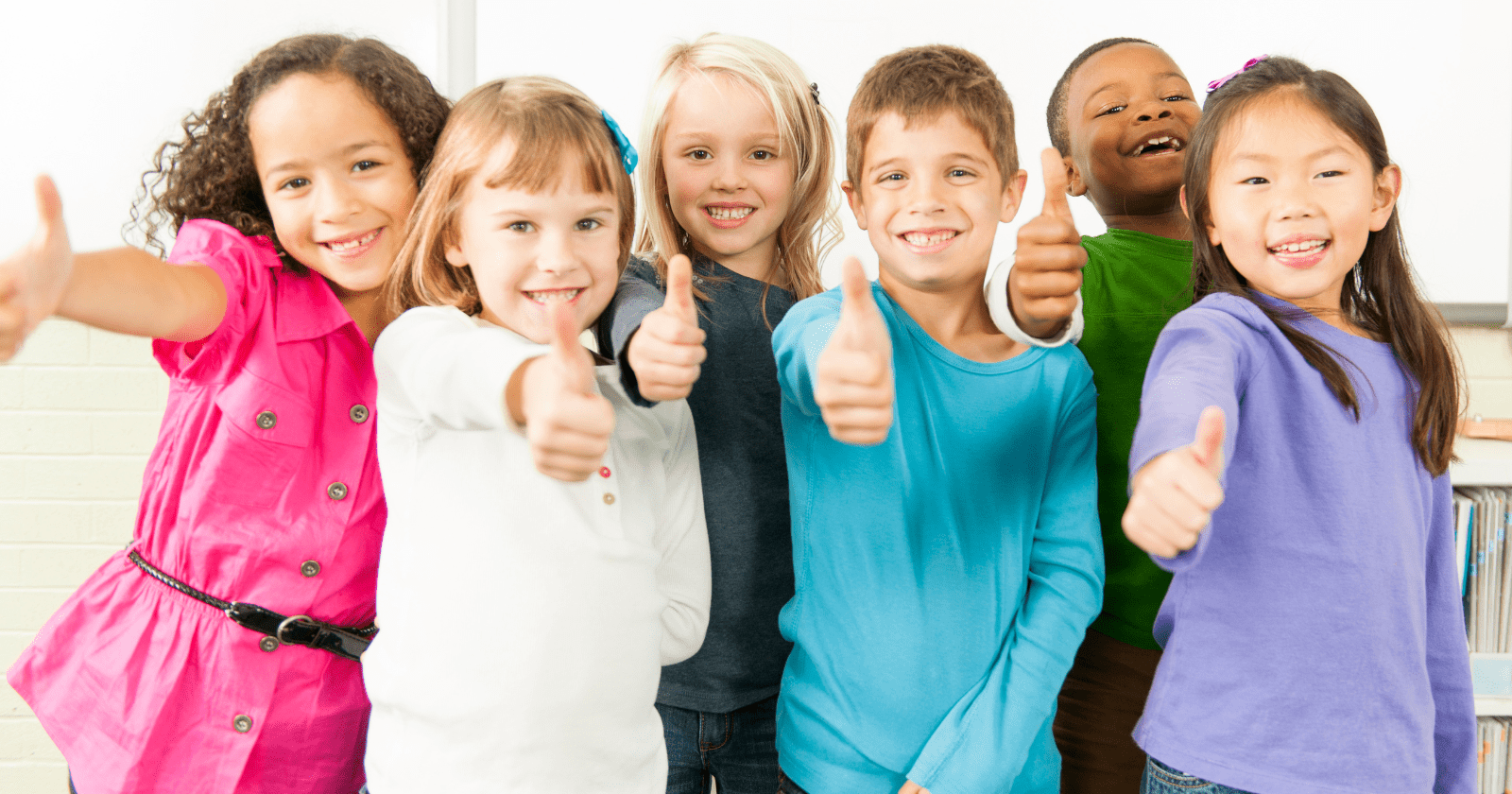 Photo shows smiling children showing thumbs up.