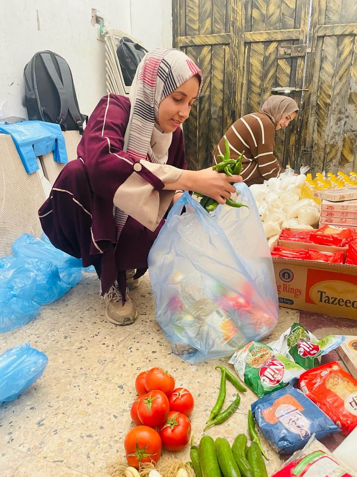 The photo shows Palestinian women taking vegetables out of bags.
