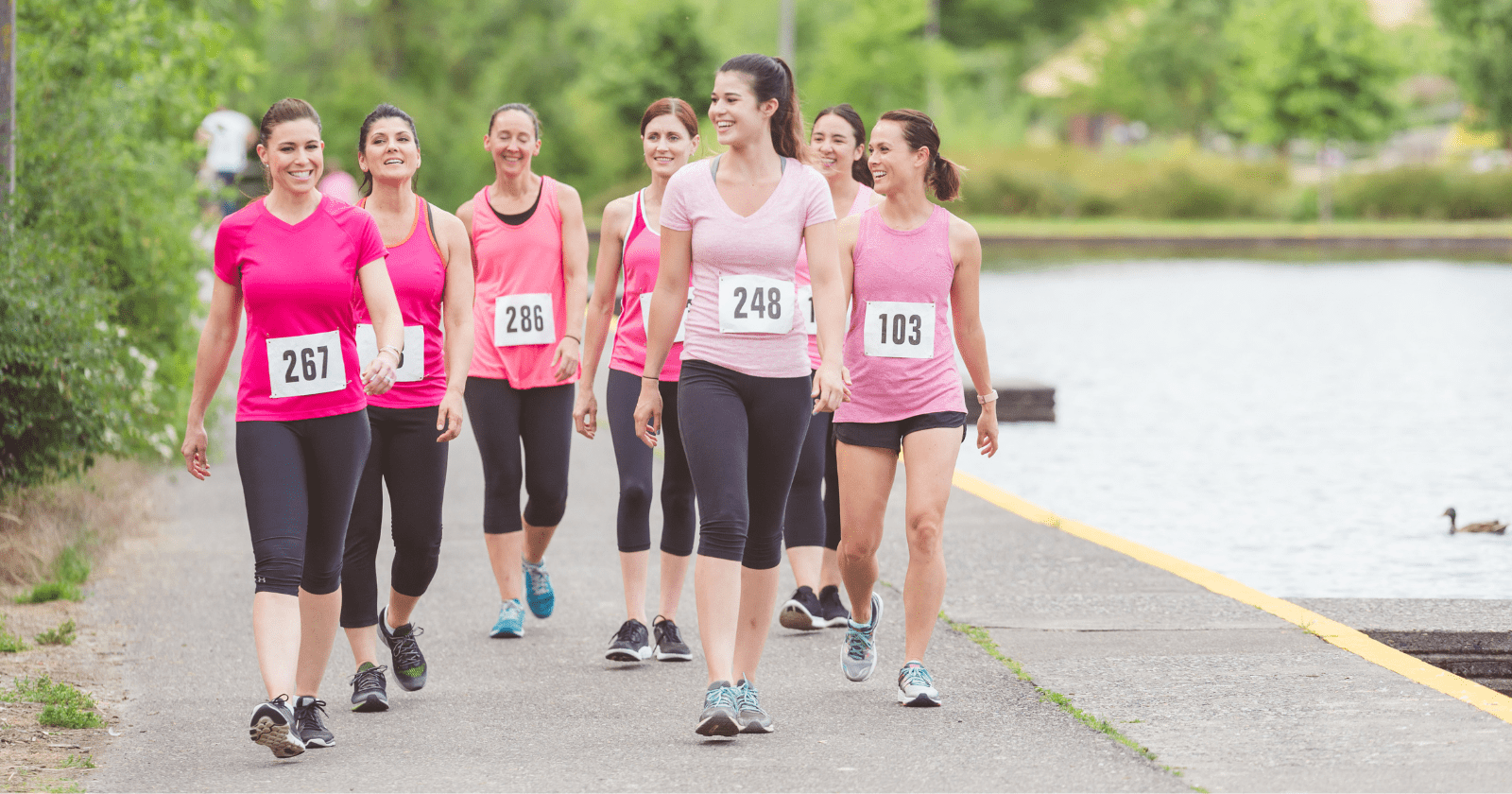 A foto mostra um grupo de mulheres alegres correndo uma maratona.