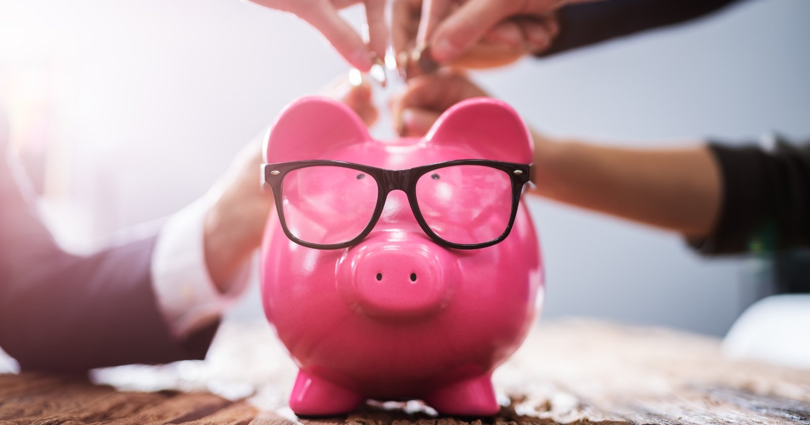 The photo shows a pink piggy bank with glasses.