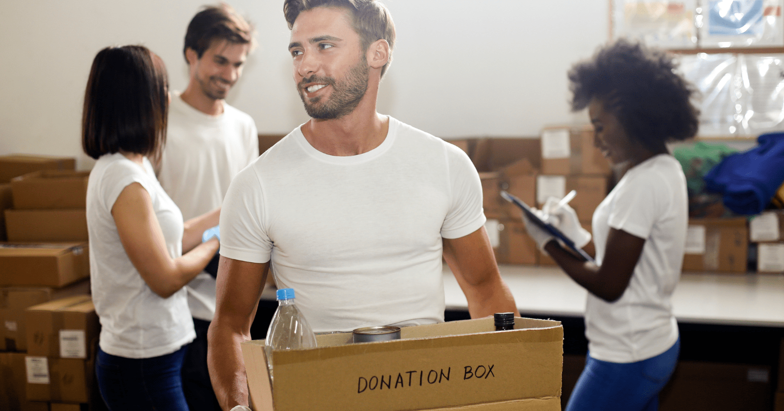 Photo shows a smiling young man with a box marked 'donation box'. In the background are other young people.