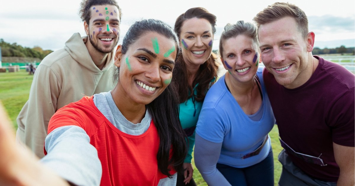 Selfie ta’ grupp ta’ nies b’wiċċhom miżbugħ b’disinji ta’ kuluri differenti